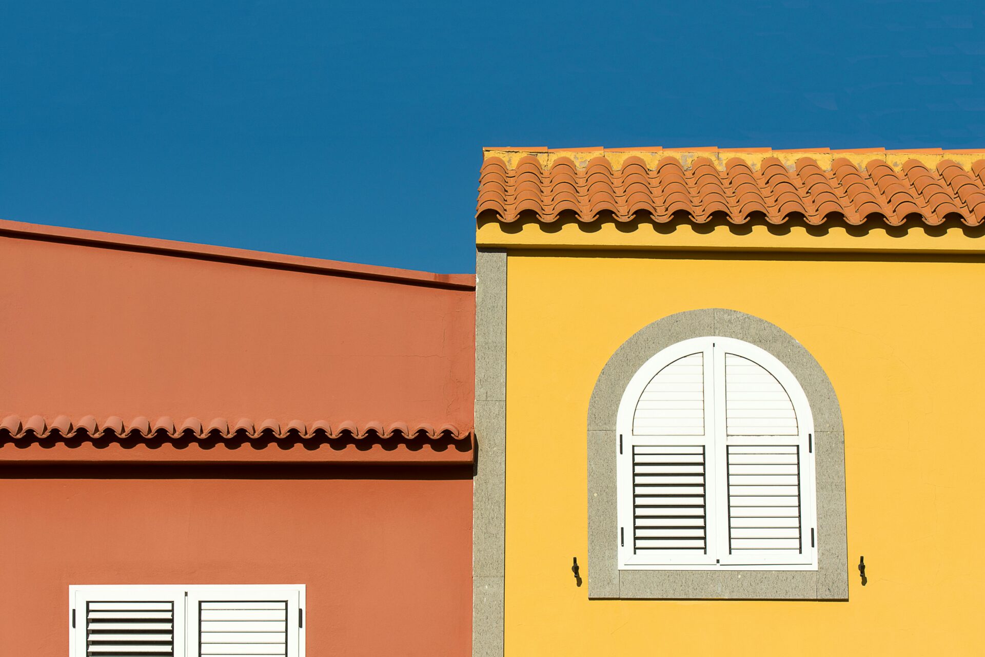 Colorful Mediterranean building facade with arch windows under clear blue sky